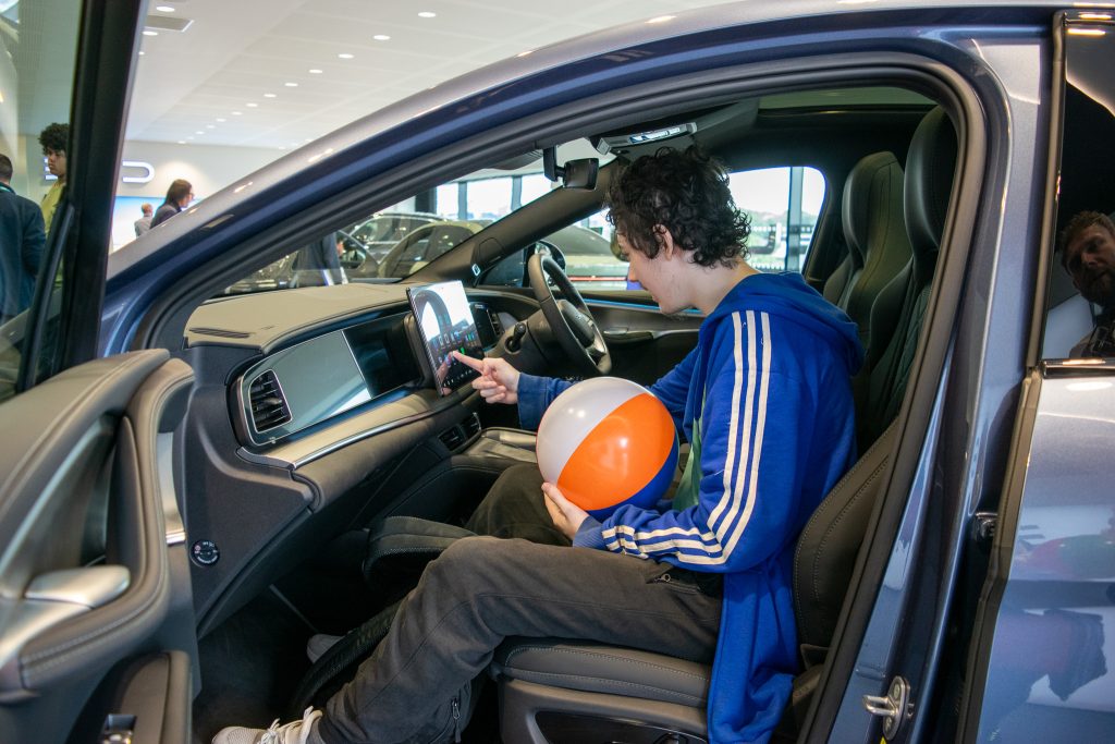 teen boy sitting in a car touching the car's digital control system