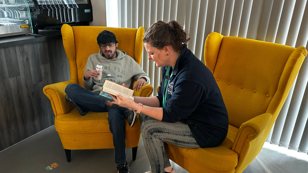 H sitting and listening to story on a bright yellow chair