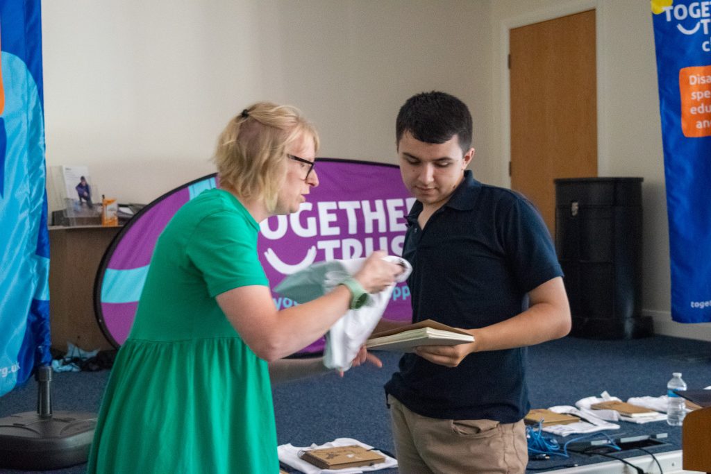 Teen boy accepting a diploma and a present from a teacher in front of the podium.