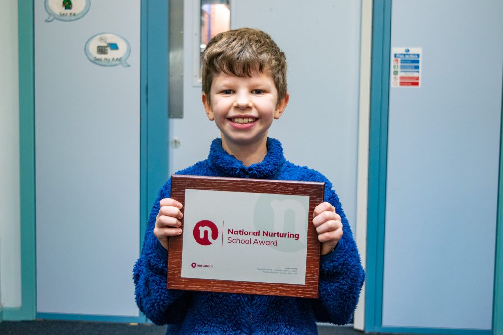 A pupil holding the certificate and smiling for a photo.