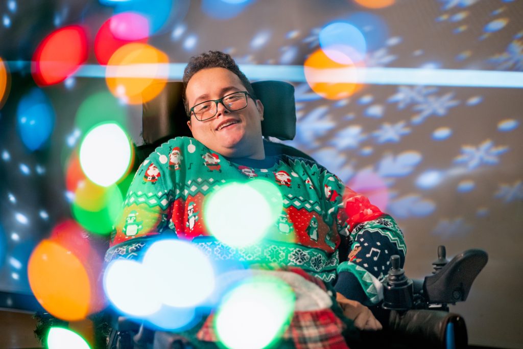 a person in a wheelchair smiling with bright colours around them