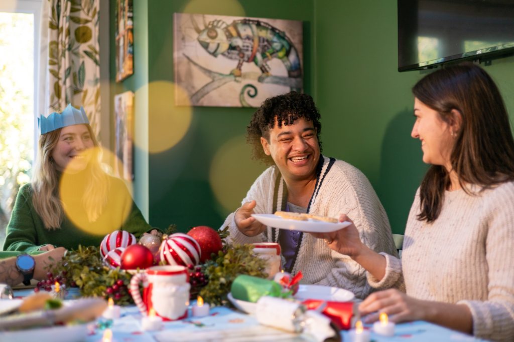 three people sat around a table passing a plate of food around