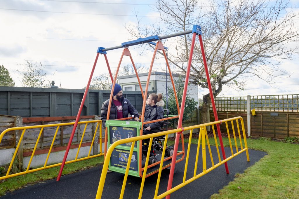 a young person and a carer enjoying an accessible swing