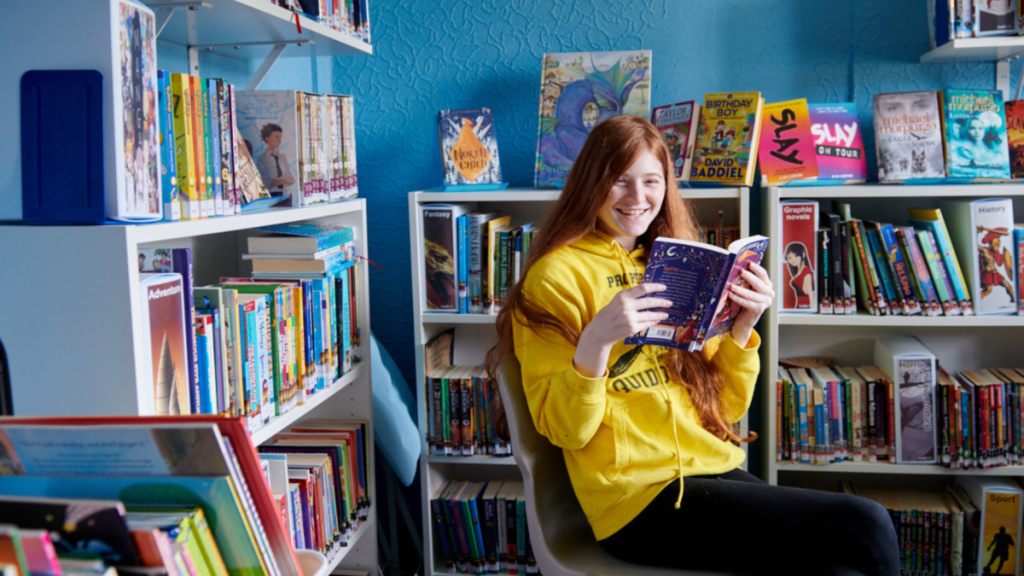 a female student reading a book in the Inscape library smiling
