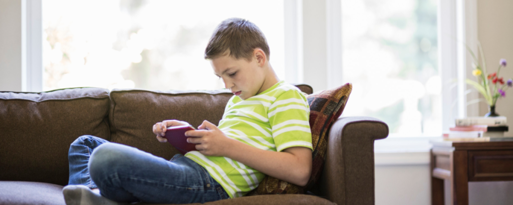 a boy sitting on a sofa reading a book