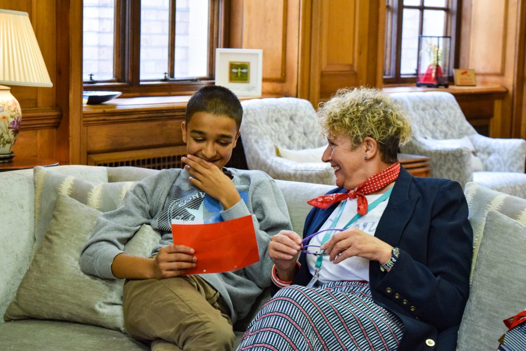 A young person and a support worker on a sofa, smiling and laughing