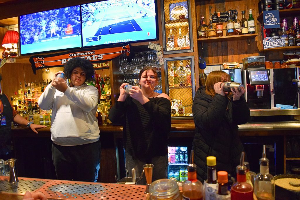 Three students crafting the classic Virgin Mojito behind the bar.