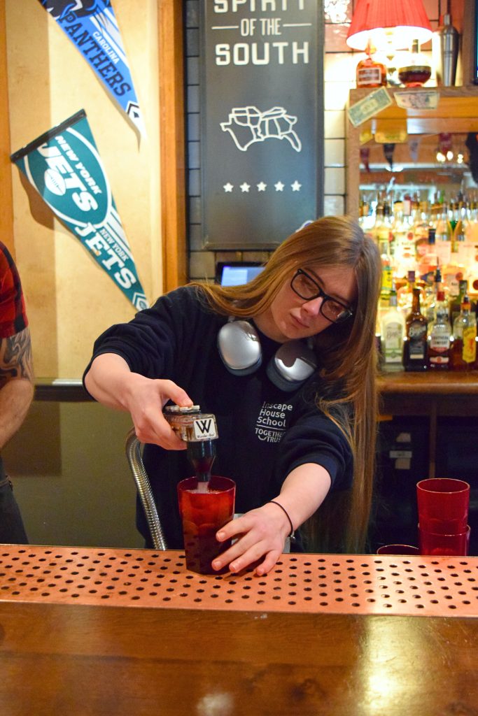 A student crafting the vibrant Bubble Blue Cooler behind the bar.