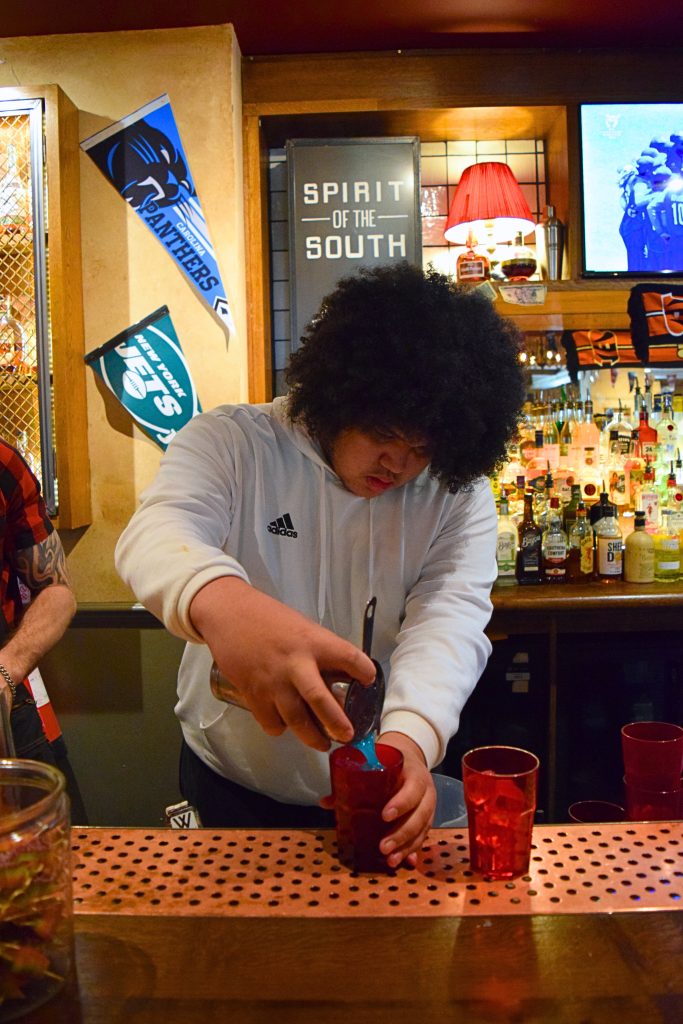 A student crafting the vibrant Bubble Blue Cooler behind the bar.