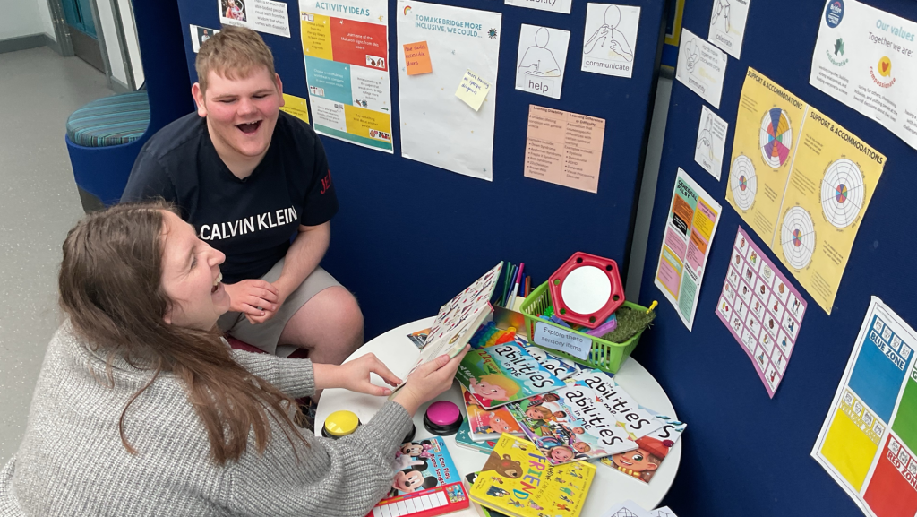Student and Bridge college colleague sat at a table of books laughing