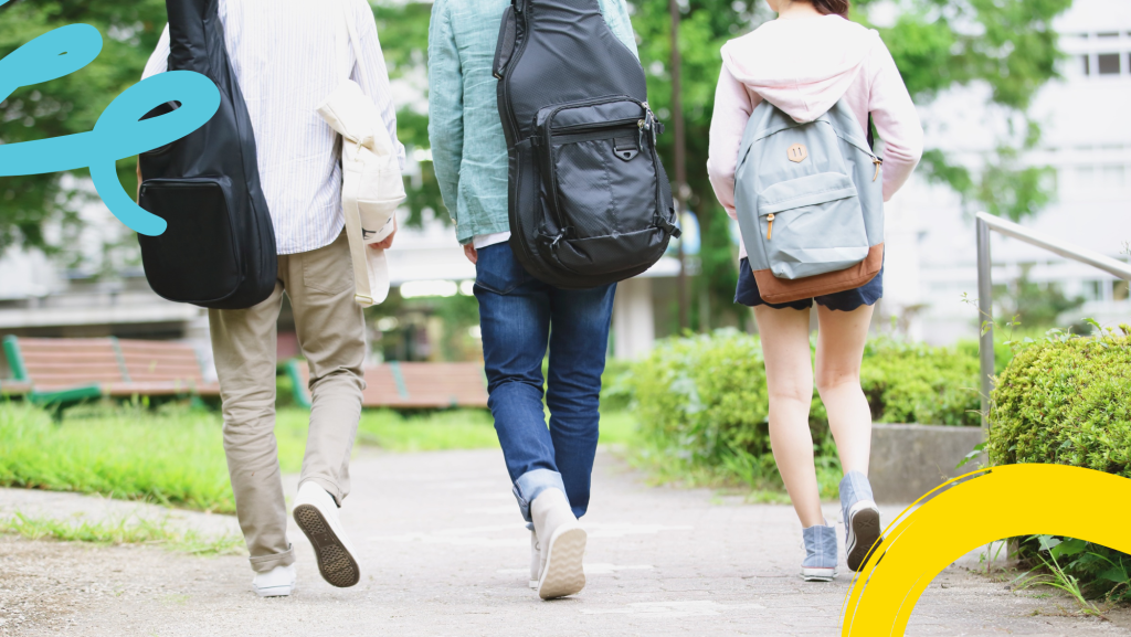 Three students walking away from the camera all carrying bags as if on their way to school.