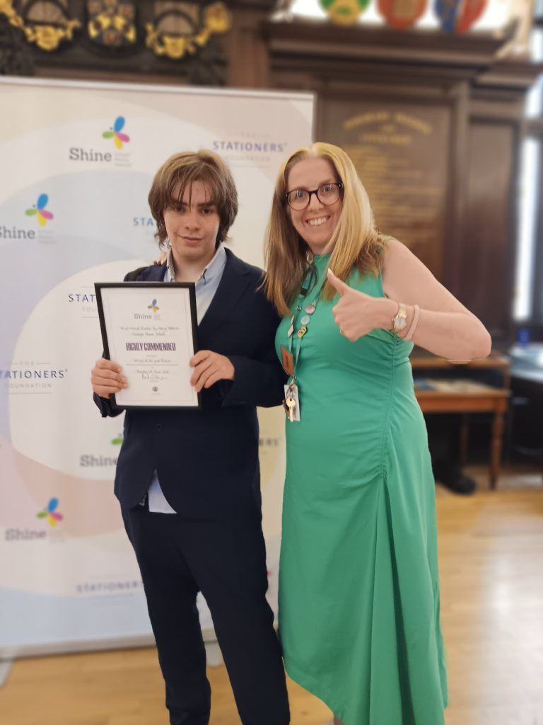 Marie, Head of careers is posing next to Harry in front of a banner. Harry is holding his certificate.