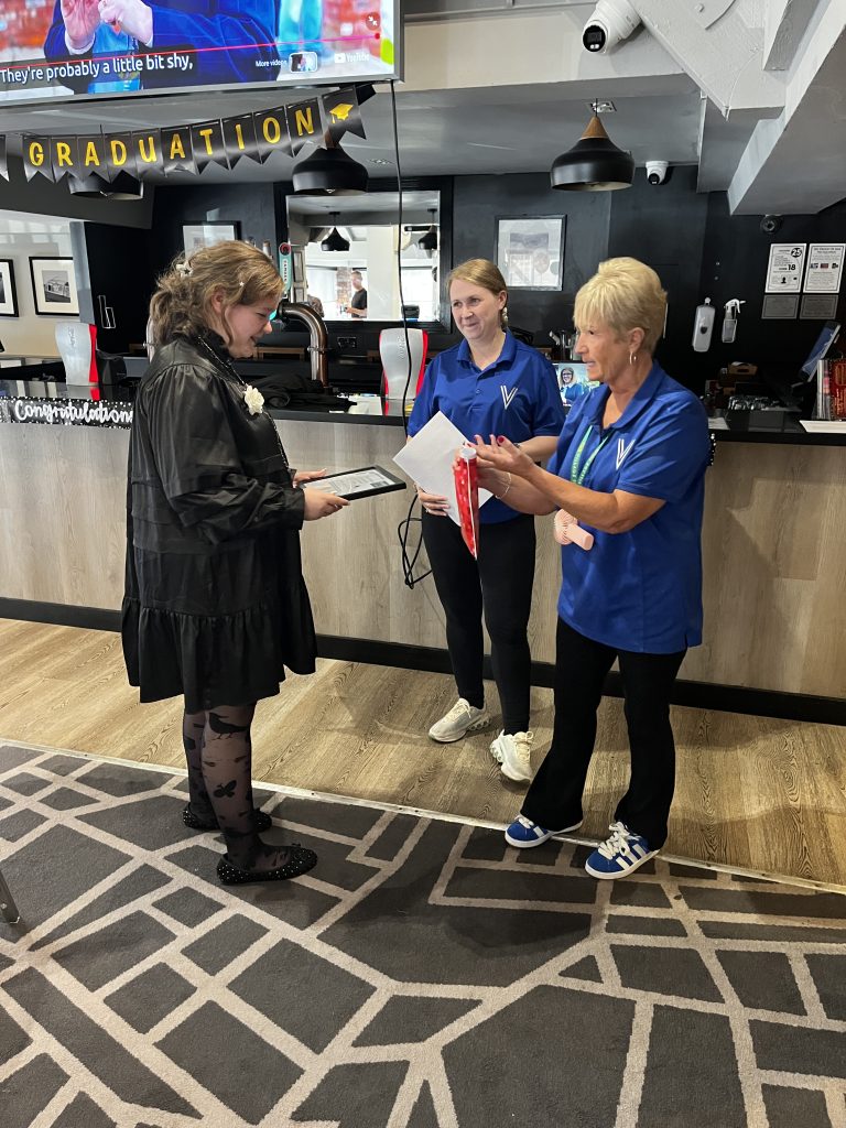 a teen is receiving a certificate and a goody bag