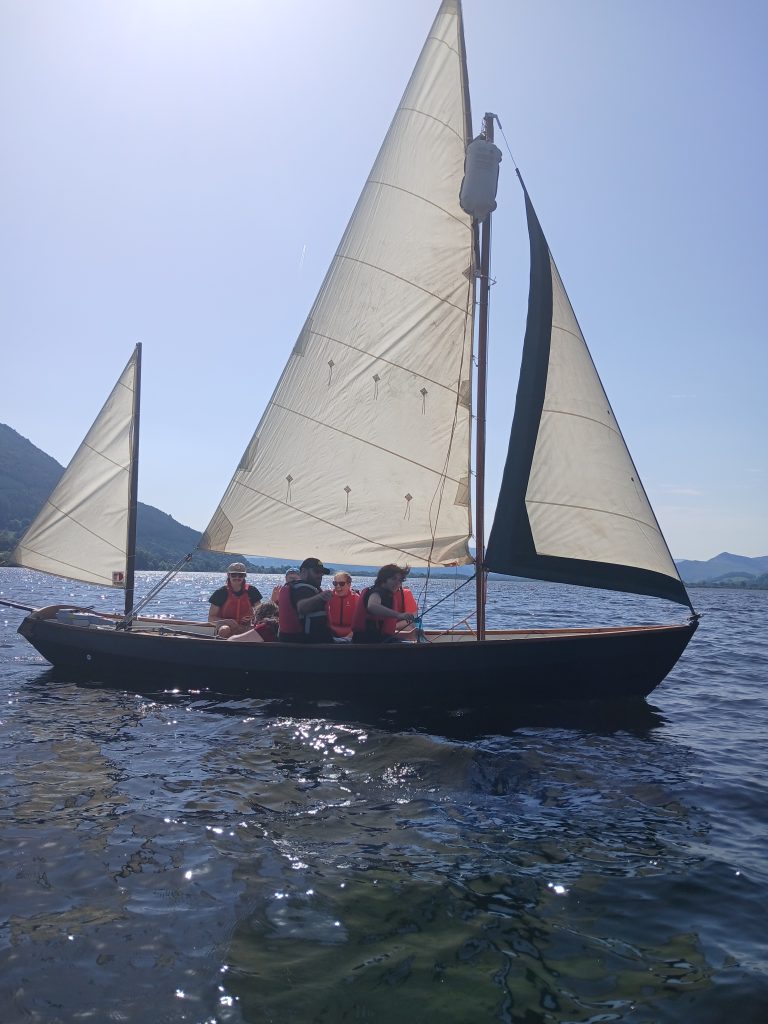 Students and staff in a sailboat on the lake
