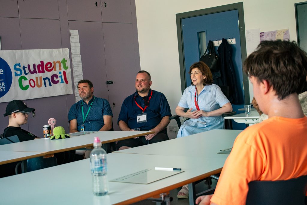 Bridge College principal John Cannon, next to Lucy powell mp and Thomas robinson councillor sat at a table talking to 2 students 