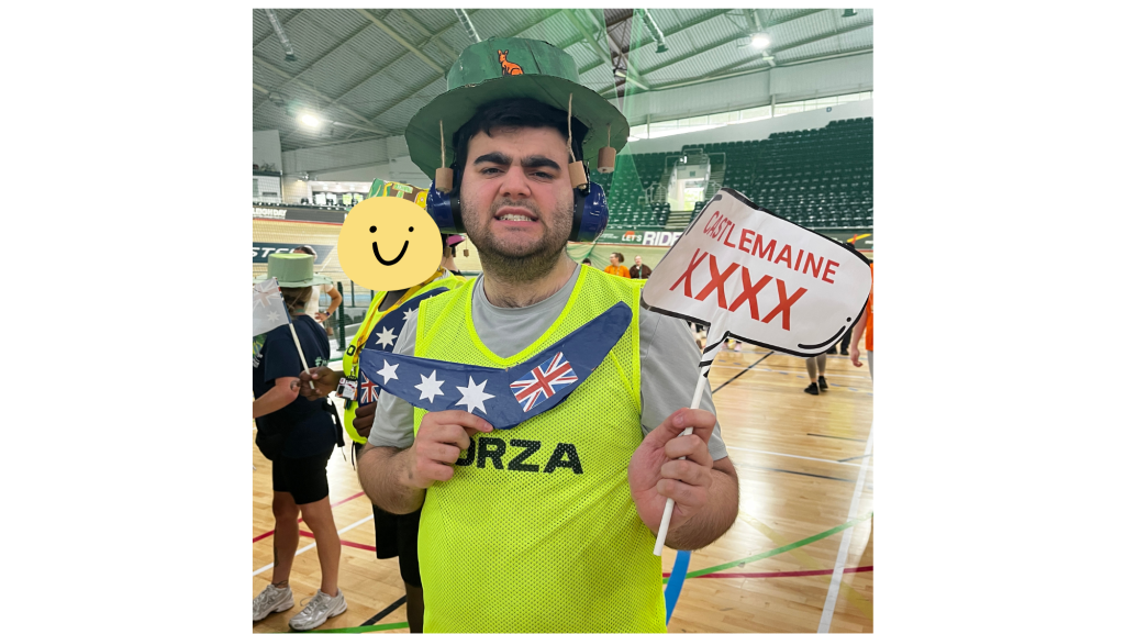 student wearing a cork-adorned sun hat holding a boomerang decorated with the Australian flag