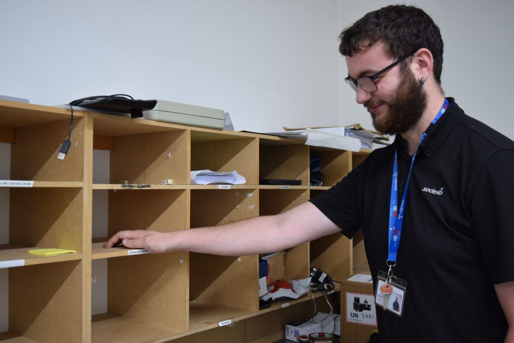 McKenzie, a young man, is sorting mail in the post room.