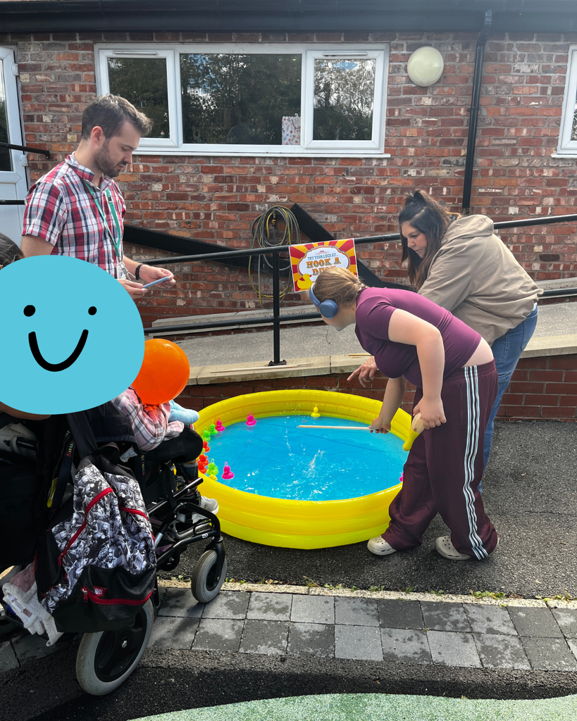 Two children playing hook a duck in an inflatable pond.