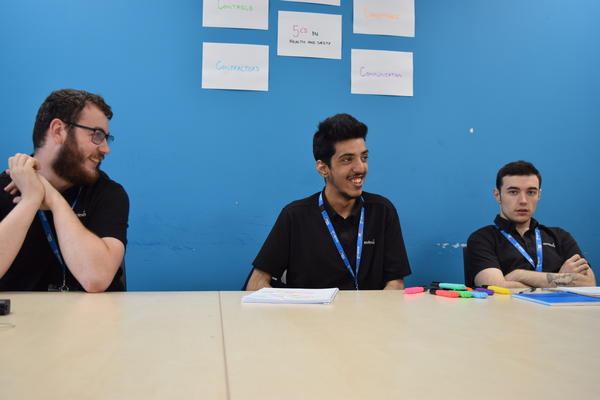 three students sat behind a table smiling at their supported internship