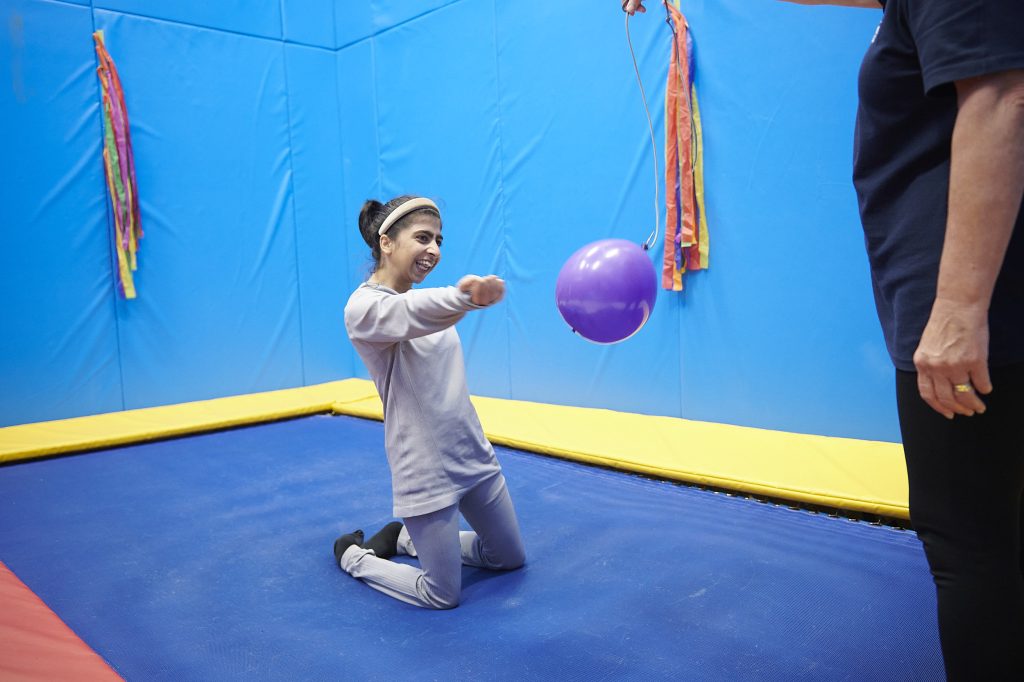 a student kneeling on a trampoline in the rebound therapy room