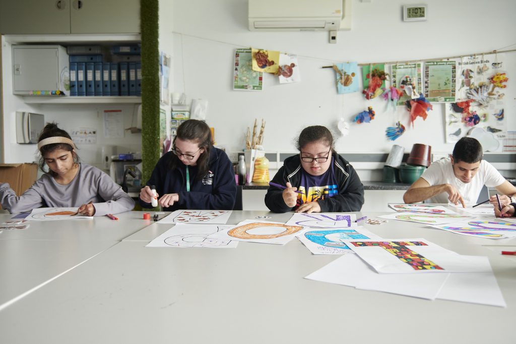 a group of students sat alongside staff in a classroom