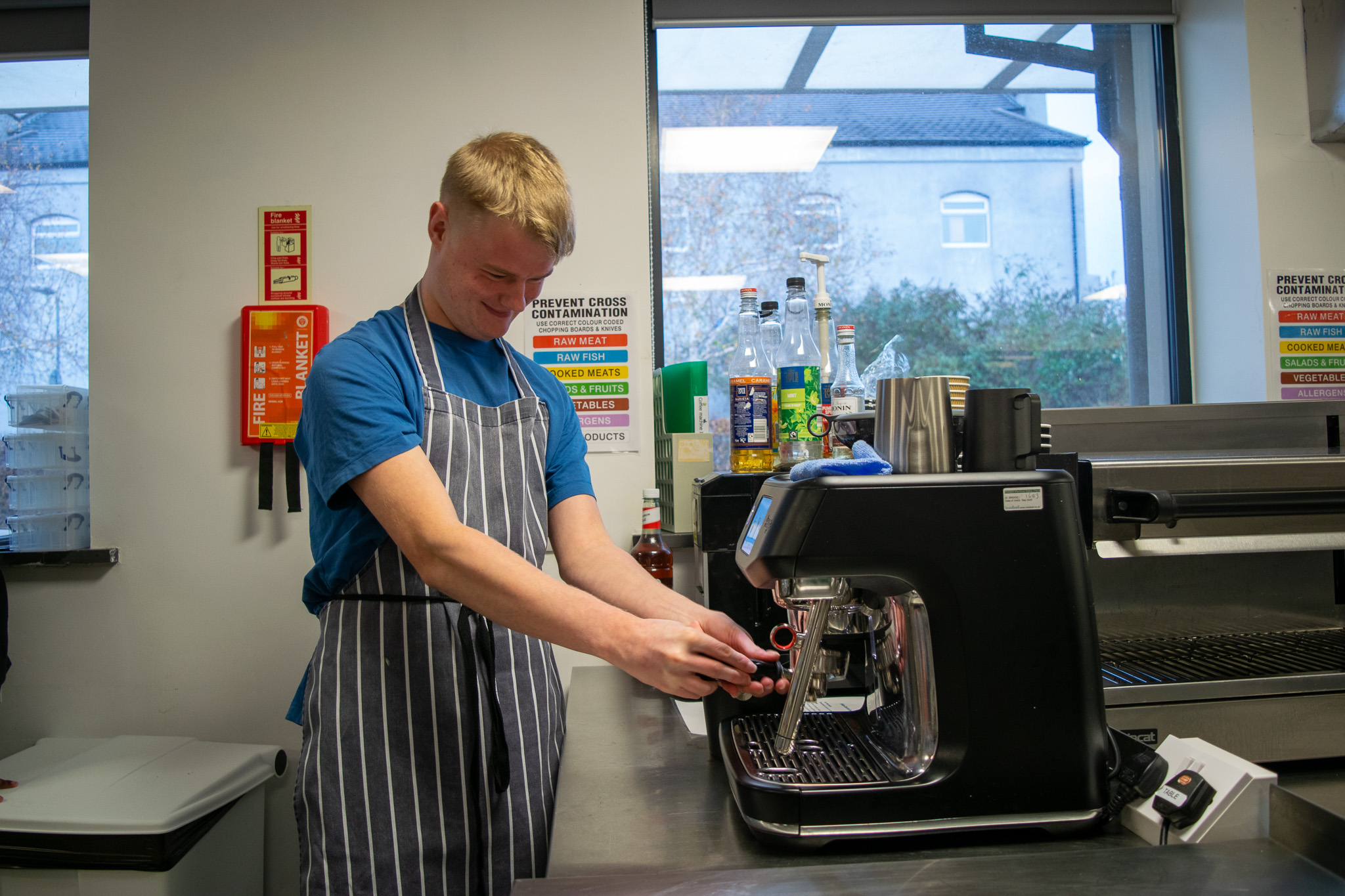A young man is operating a coffee machine