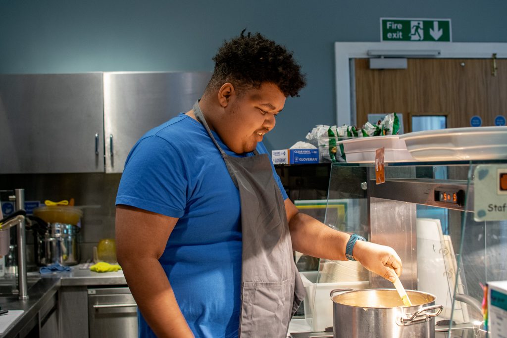 a student staring a pot of food in the cafe at inscape
