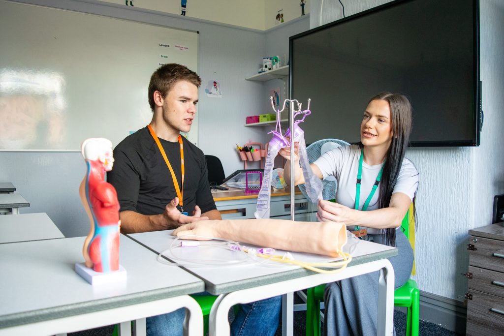 a student and a teacher with a fake arm learning connected to tubes