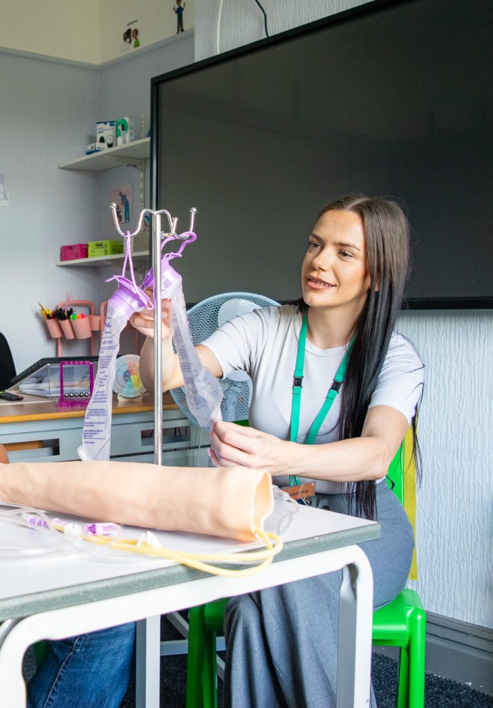 a student and a teacher with a fake arm learning connected to tubes