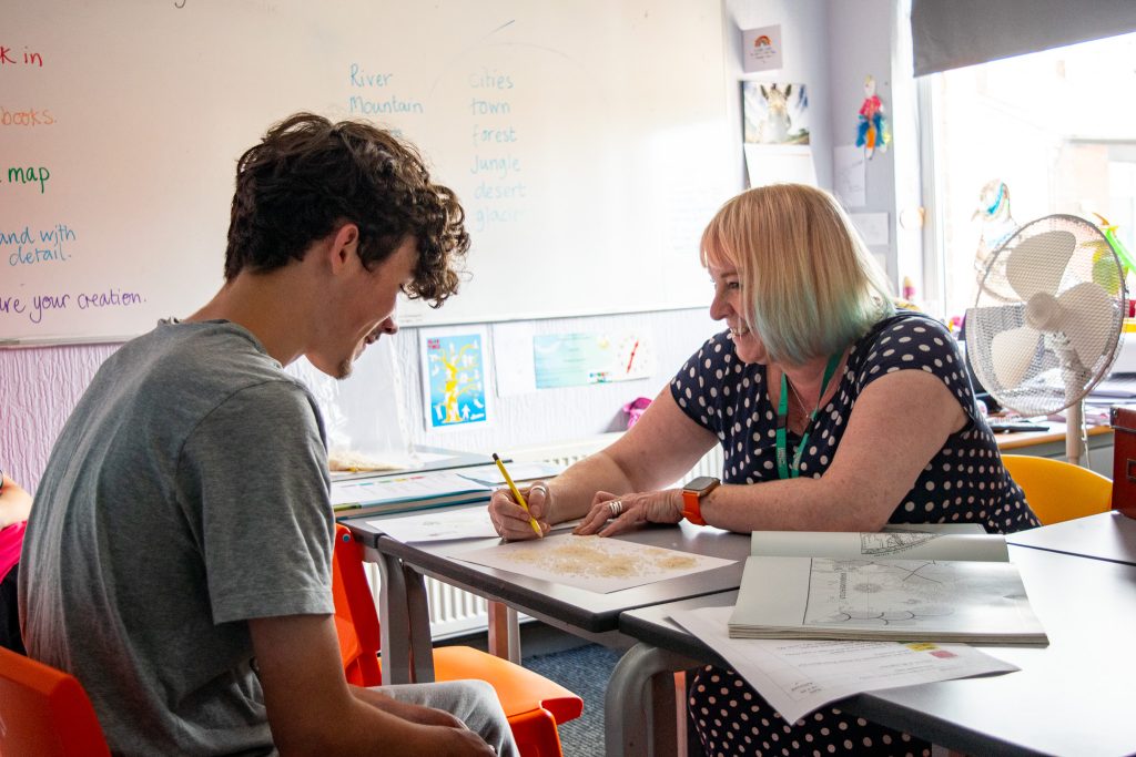 a college student sat opposite a teacher who is writing
