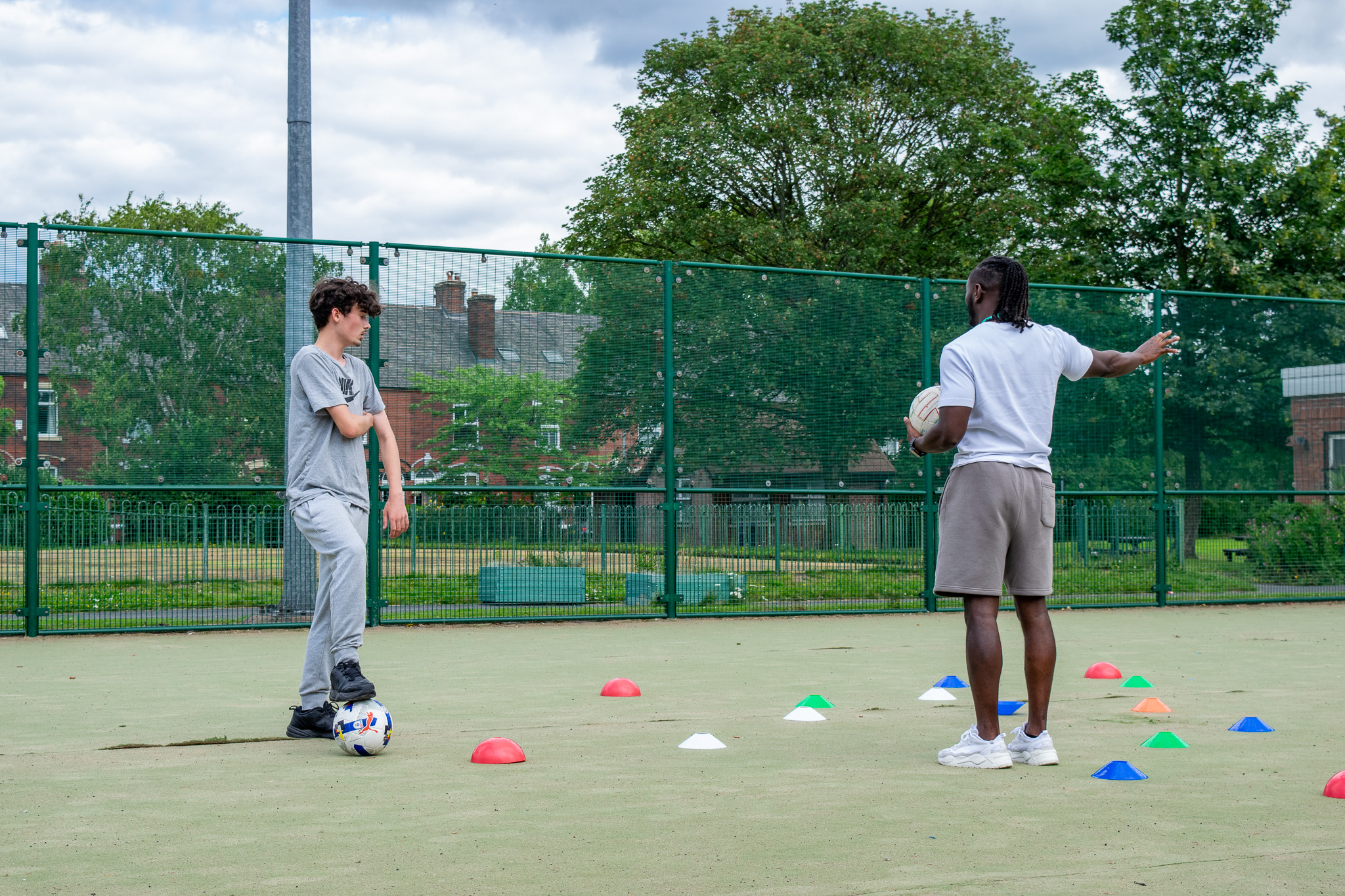 a student and teacher talking on a football pitch